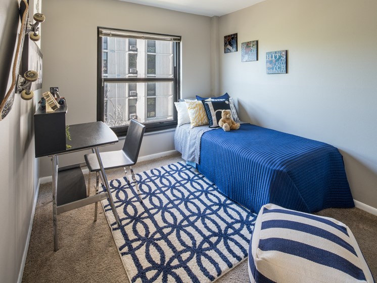 Bedroom photo with large window and blue furnishings